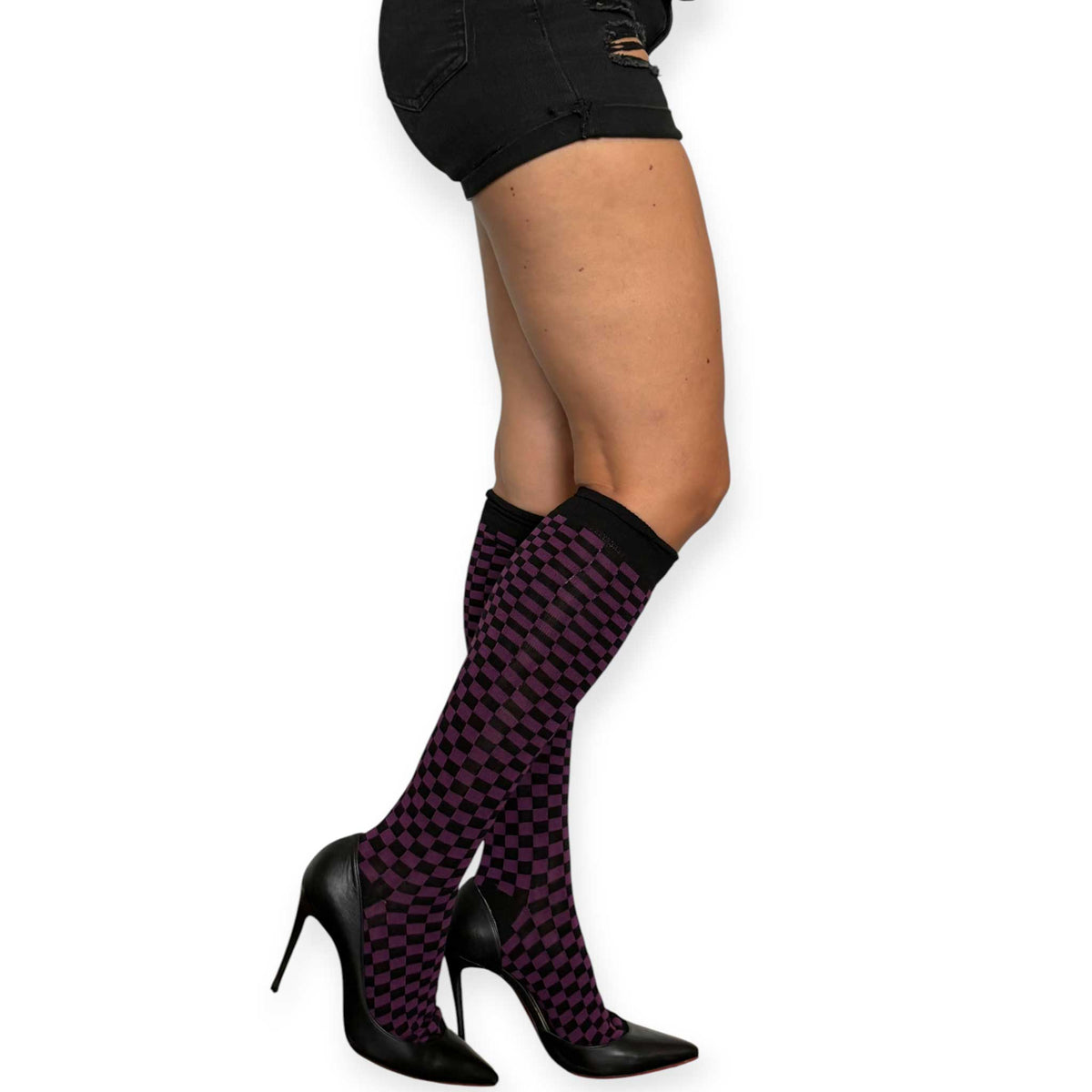 Purple and black checkerboard knee-high socks for women by Malka Chic styled with black shorts and pointed heels.