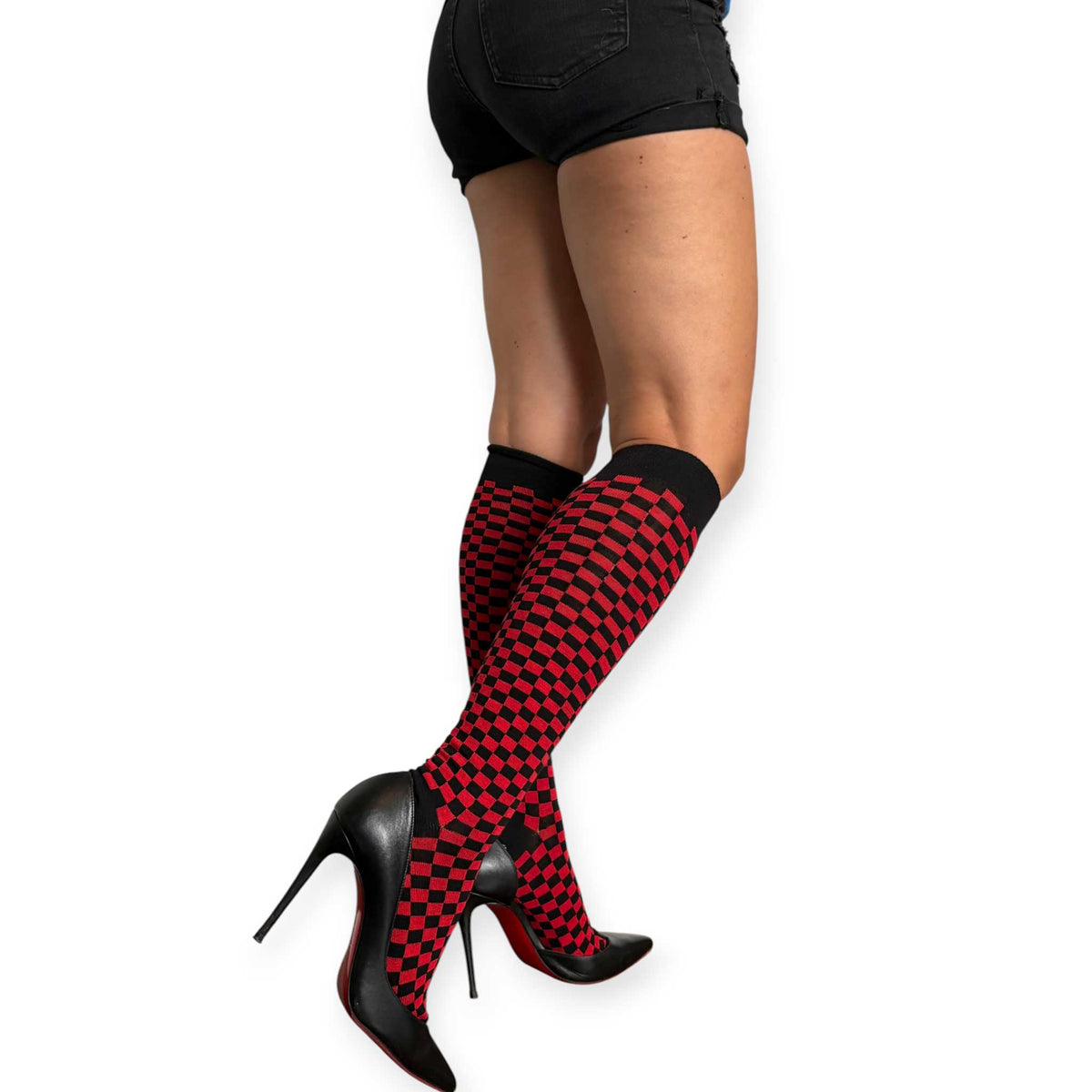 Red and black checkerboard knee-high socks for women by Malka Chic styled with black shorts and pointed heels.