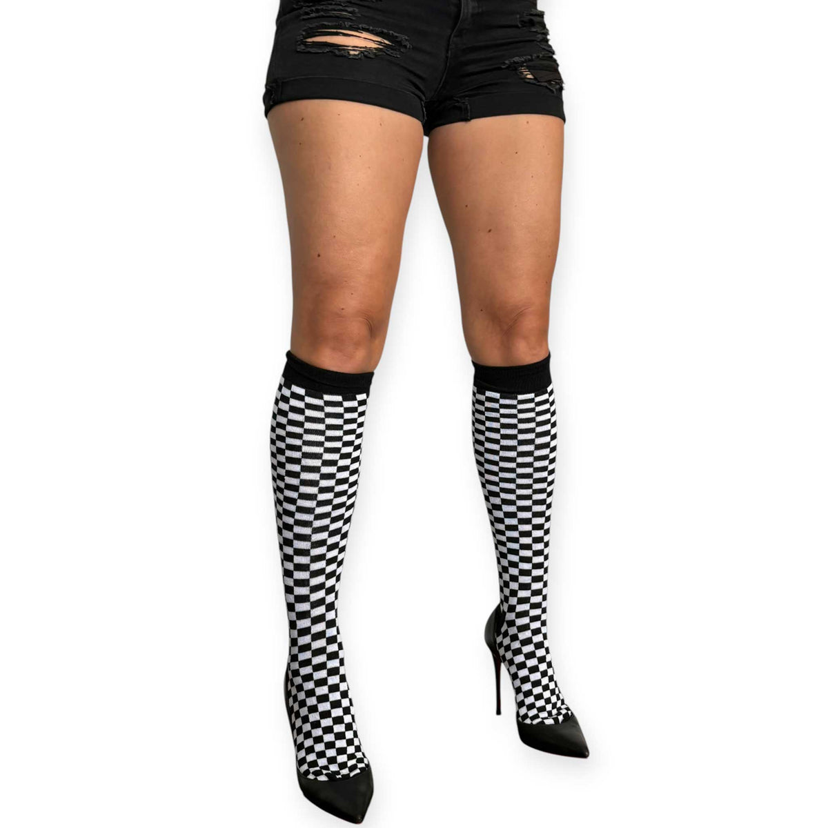 Women’s checkerboard knee-high socks by Malka Chic styled with black high-waisted shorts and heels.