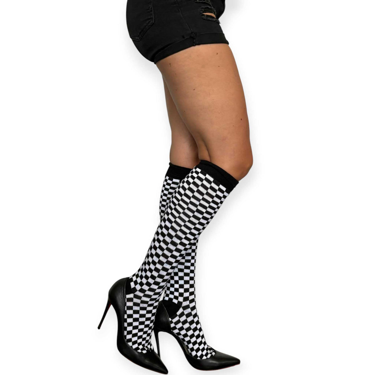 Black and white checkerboard knee-high socks for women by Malka Chic styled with black shorts and pointed heels.