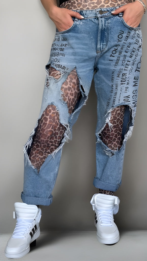 Person wearing distressed blue jeans with leopard print patches sold at Malka Chic