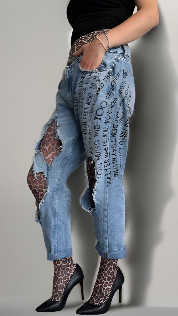 Person wearing distressed blue jeans with text pattern and leopard print tights sold at Malka Chic